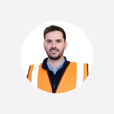 Man wearing an orange safety vest, circular cropped portrait photo.