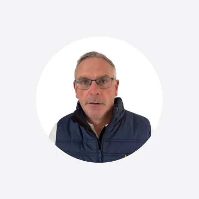 Middle-aged man with glasses wearing a navy jacket, circular cropped portrait photo.