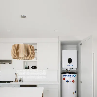 White kitchen with a heat pump water heater installed in a recessed alcove beside cabinetry.