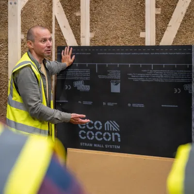 Man in yellow safety vest presenting an Eco Cocon display board at a construction site.