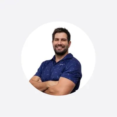 Smiling man in a navy polo shirt with arms crossed, circular cropped photo.