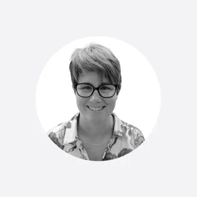 Black and white portrait of a smiling woman with short hair and glasses.