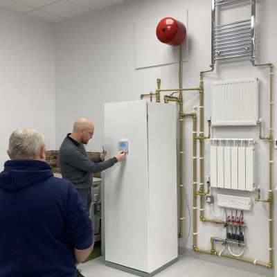 Three people examining a heating system installation with pipes and a radiator in a technical room.