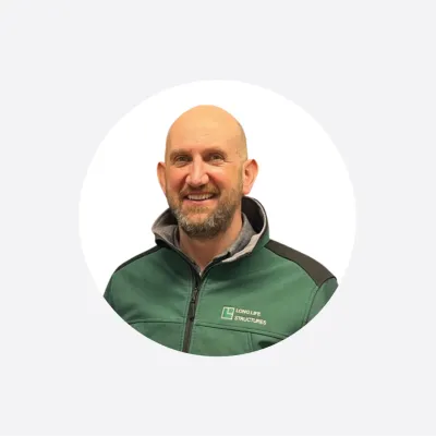 Smiling bald man wearing a green and gray zip-up jacket, circular profile photo.
