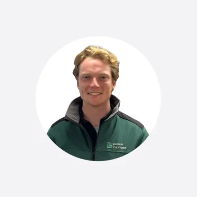 Smiling young man with light brown hair wearing a dark green jacket, circular cropped photo.