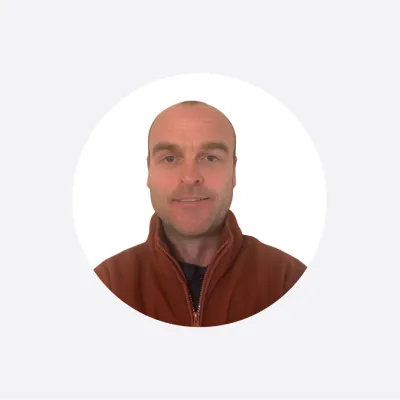 Portrait photo of a middle-aged man in a rust-colored jacket, circular crop.