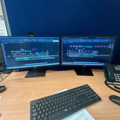 Dual monitors displaying colorful code on a desk with a wireless keyboard.