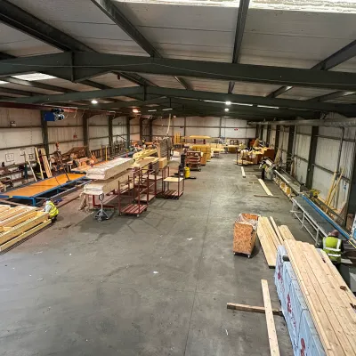 Aerial view of a large industrial warehouse with timber, machinery, and a concrete floor.
